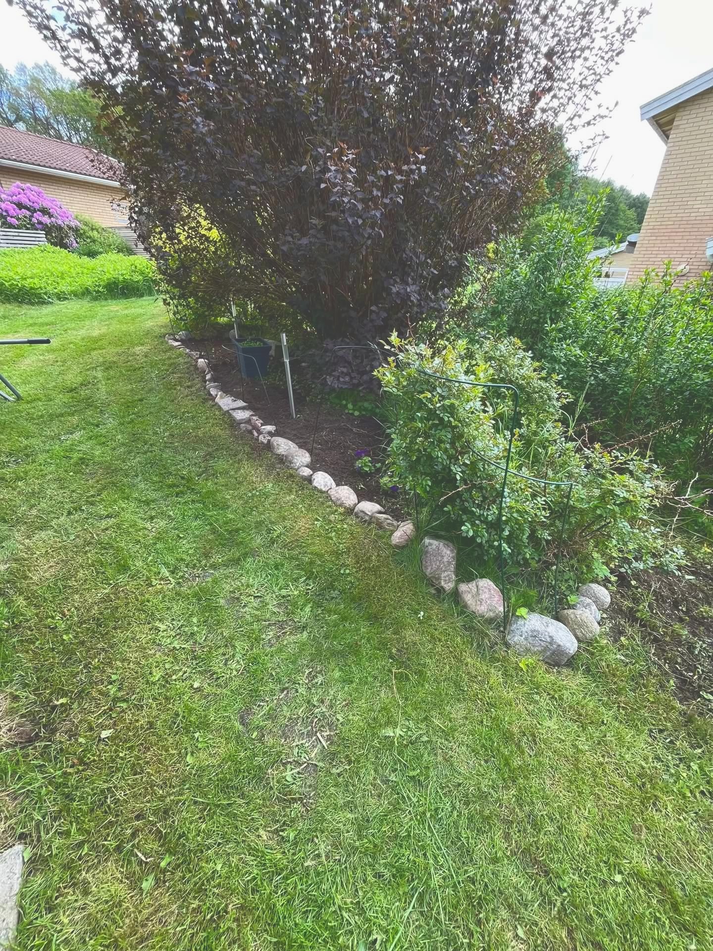 Välskött rabatt med natursten runt planteringen